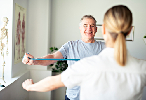 Man exercising with resistance band and physical therapist