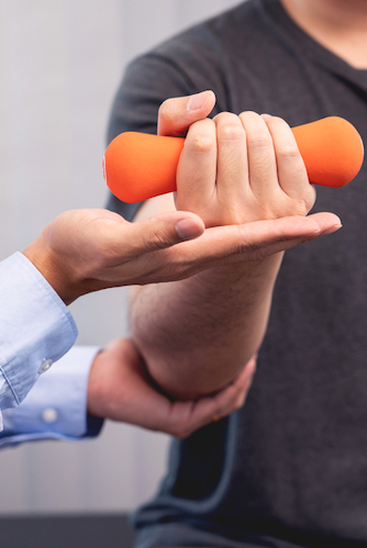 Person holding dumbell during exercise rehabilitation
